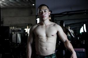 sexig kropp av muskulös ung soldat asiatisk man i Gym. begrepp av hälsa vård, övning kondition, stark muskel massa, kropp förbättring, fett minskning för herr- hälsa tillägg produkt presentation. foto