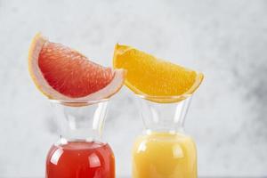 två glas grapefrukt och apelsinjuice på en stenbakgrund foto