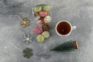 färgglada söta munkar med en julgranleksak och en kopp varmt te foto