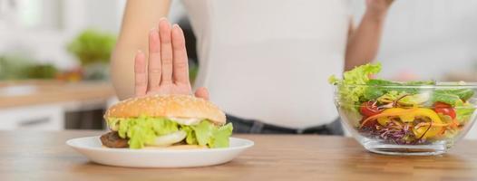 diet, bantning asiatisk ung kvinna eller flicka skjuta på ut, förneka hamburgare, skräp mat och välja grön äpple, blanda grönsaker sallad, äta mat för Bra friska, hälsa när hungrig. kvinna vikt förlust människor. foto