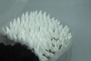 en knippa av svart och spetsig vit bomull knoppar inuti transparent behållare isolerat på enkel vit bakgrund. foto