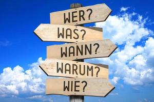 WHO, Vad, när, Varför, på vilket sätt frågor i tysk - trä- vägvisare med fem pilar foto