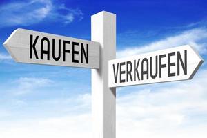 köpa, sälja - i tysk - trä- vägvisare med två pilar och himmel i bakgrund foto