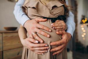 mannens händer omfamning en mage av de gravid kvinna foto