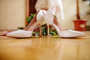 kvinna fötter i vit bröllop sandaler med en bukett av camomiles foto