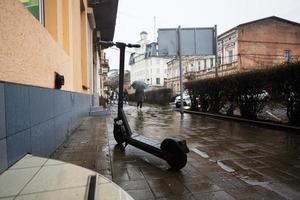 elektrisk skoter stå i regn stad gata. foto