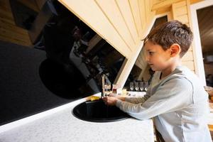 pojke tvättar händer i de handfat på kök i mysigt trä- mycket liten stuga hus. liv i landsbygden. foto