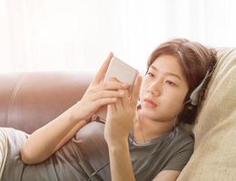 asiatisk kvinna lyssnande musik från mobil telefon foto