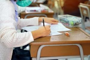 asiatisk skola barn ta prov till mäta och bedöma inlärning resultat. under de epidemi situation av de korona virus förbi bär en mask Allt de tid. mjuk och selektiv fokus. foto