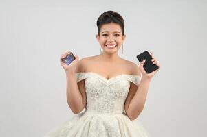 ung asiatisk skön brud inlägg med kreditera kort och smartphone i hand foto