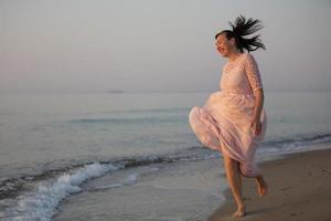 en skön medelålders kvinna i en klänning kör längs de stranden. foto