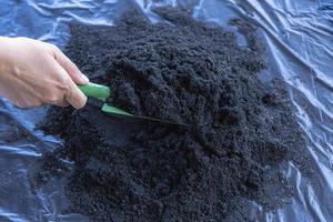 förberedelse av jord blandning från bördig kompost, humus och vermikulit på svart sopor väska golv i trädgård. blandning de jord komponenter för de förberedelse av de substrat för transplantation växter. foto