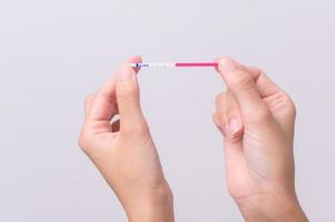stänga upp kvinna använder sig av ovalering lh testa eller hcg graviditet testa på vit bakgrund foto