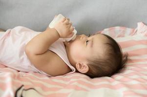 en bebis flicka är dricka mjölk flaska, familj, barn, barndom och föräldraskap begrepp foto