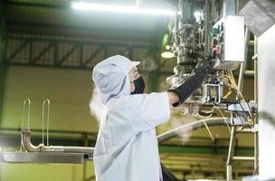 kvinna arbetstagare i en ketchup fabrik kontrollerade automatisk aseptisk fyllning maskin fyllning ketchup in i stor kar på ett industriell anläggning i Asien. mat industri jordbruksindustrin. foto