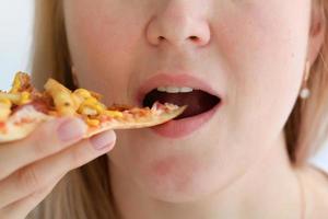 kvinna äter med bra nöje, kvinna äter pizza, mat. foto