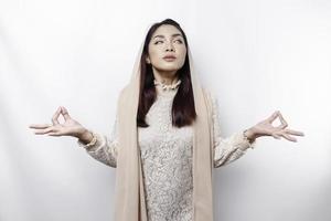 asiatisk muslim kvinna praktiserande yoga och mediterar utgör med stängd ögon isolerat förbi vit bakgrund foto