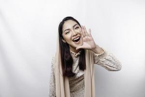 ung skön asiatisk muslim kvinna bär en slöja skrikande och skrikande högt med en hand på henne mun. kommunikation begrepp. foto