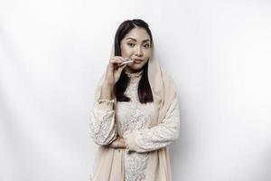 porträtt av en ung skön asiatisk muslim kvinna bär en slöja innehav henne läppstift foto