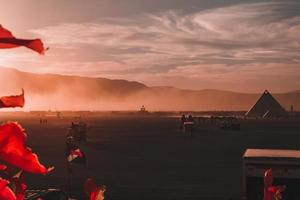 människor gående mot solnedgång på en festival i de öken- på de brinnande man festival. foto
