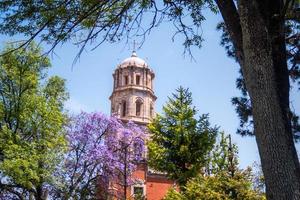 jacaranda träd lila blommor bakgrund av tempel av san francisco de i befintligt skick i queretaro mexico foto