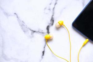 gula öronknoppar anslutna till smart telefon foto
