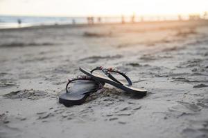 flip flops på strand med sandig strand solnedgång och hav hav foto