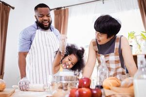 Lycklig afrikansk amerikan familj njut av tillsammans medan förbereda de mjöl för framställning småkakor på Hem foto