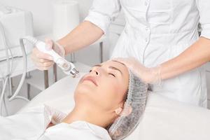 kosmetolog gör ansiktsbehandling gas flytande syre serum epidermal peeling för föryngring kvinna ansikte foto