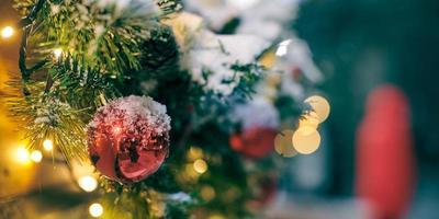 jul träd lökar med gul kransar täckt snö, utomhus- xmas träd med dekorativ röd lökar foto