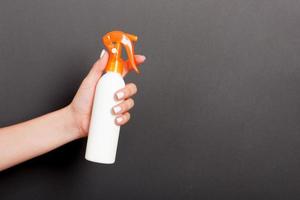 kvinna hand innehav spray grädde flaska av lotion isolerat. flicka ge kosmetisk Produkter på svart bakgrund foto