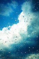 regndroppar på ett fönster med moln foto