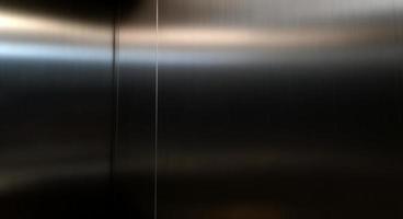 rostfri stål stor ark med ljus slå de yta, inuti passagerare hiss, reflektion av ljus på en skinande metall konsistens, rostfritt stål bakgrund, metall textur bakgrund. foto