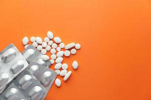 vita piller och blisterförpackning på orange bakgrund