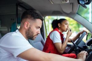 två paramedics i de främre av ett ambulans. de fokus är på de man, en ung man i hans 20s ser genom de öppen förarens sida fönster. foto