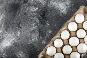 råa kycklingägg i en ägglåda på marmorbakgrund