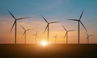 silhuett av vind turbiner fält mot solnedgång himmel bakgrund. väderkvarn, eco kraft. grön energi teknologi begrepp foto