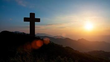 silhuetter av kristen korsa symbol på topp berg på soluppgång himmel bakgrund. begrepp av crucifixion av Jesus Kristus. foto