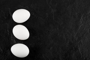 tre vita ägg på en svart bakgrund foto