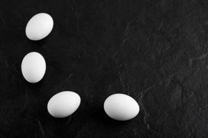 färska vita ägg på en svart bakgrund foto