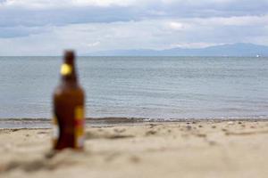 flaska av öl på de sand förbi de hav. selektiv fokus.flaska av öl på de strand. foto