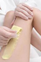 närbild se av kosmetolog avlägsnande hår på kvinna ben använder sig av varm vax i professionell skönhet salong foto