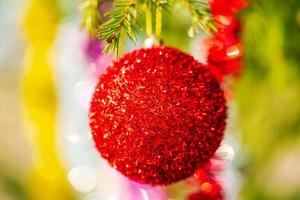 ljus röd jul boll och lysande glitter hängande på gren av träd. närbild se av xmas Semester sammansättning för Lycklig ny år foto