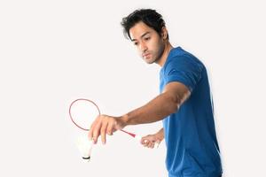 en badminton spelare i sportkläder står innehav en racket och fjäderboll. foto