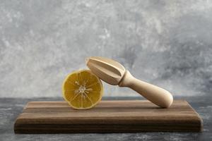 skivad citron med en träreamer på en träskiva foto