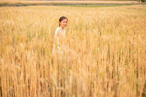 ung asiatisk kvinnor i vit klänningar i de korn ris fält foto