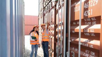 asiatisk kvinna ingenjör med notera Urklipp och asiatisk man handledare i hård hattar och säkerhet västar stå i behållare terminal. behållare i exportera och importera företag och logistik. foto