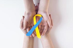blå gul medvetenhet band på portion hand för värld ner syndrom dag wdsd Mars 21 höjning Stöd på patient med ner syndrom sjukdom handikapp och bröstkorg utlopp syndrom tos foto