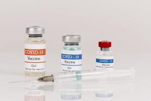 covid-19 vaccinflaskor med spruta på vit bakgrund