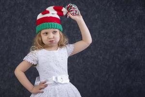 rolig liten blond i en stickat jul hatt med en pompom. Lycklig skön barn handla om fem år gammal. foto